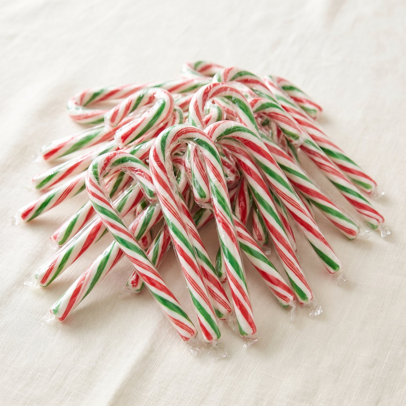 A pile of individually wrapped peppermint candy canes with red, green and white stripes